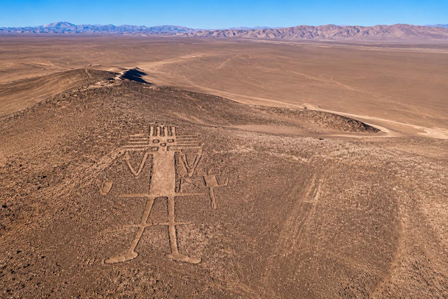 Aerial view of the Atacama Giant geoglyph on Cerro Unitas in northern Chile, surrounded by the vast Atacama Desert.